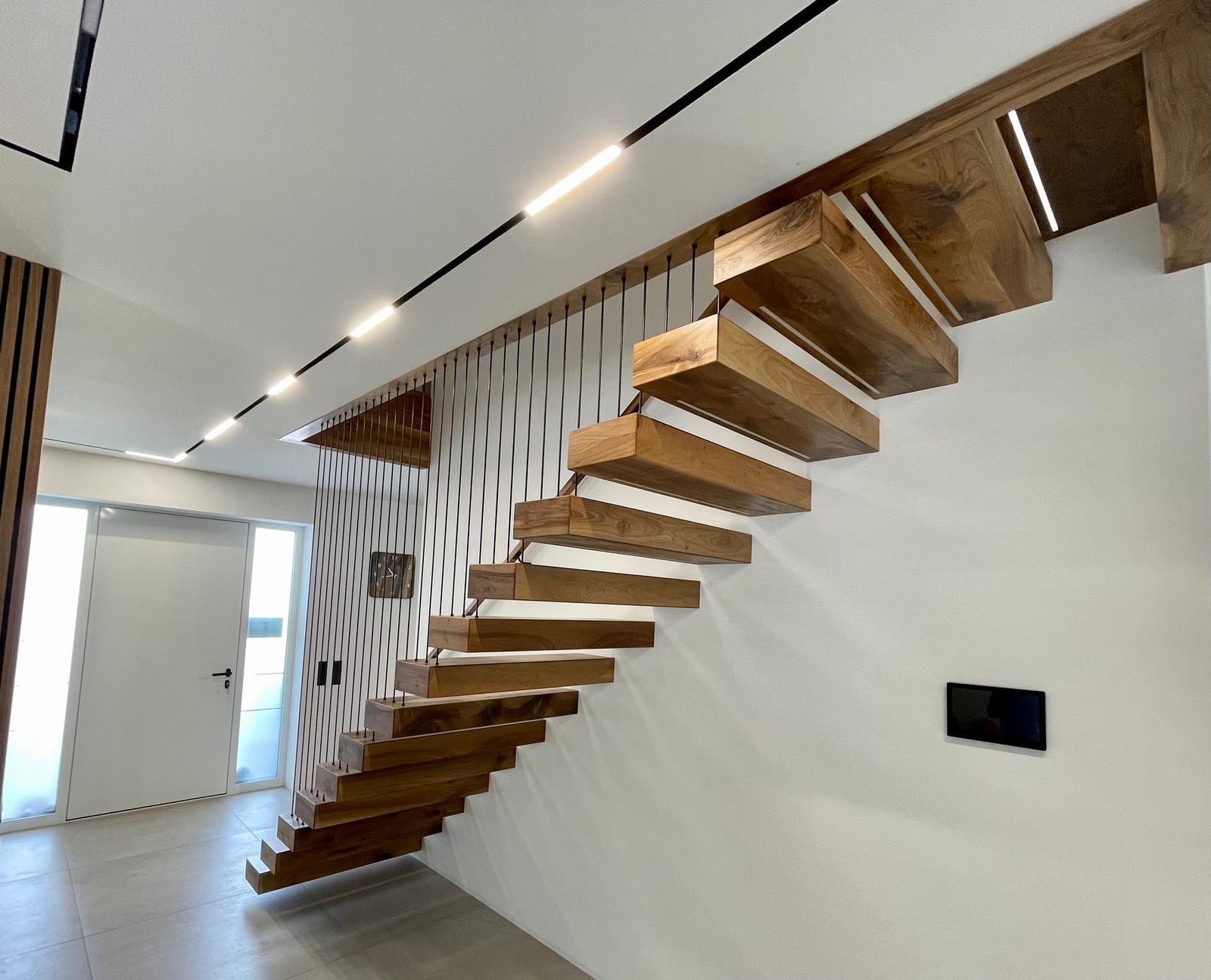 Kragarmtreppe in Nussbaum mit senkrechten Stäben als Absturzsicherung, LED-Lichtband an der Decke – AN Treppenbau