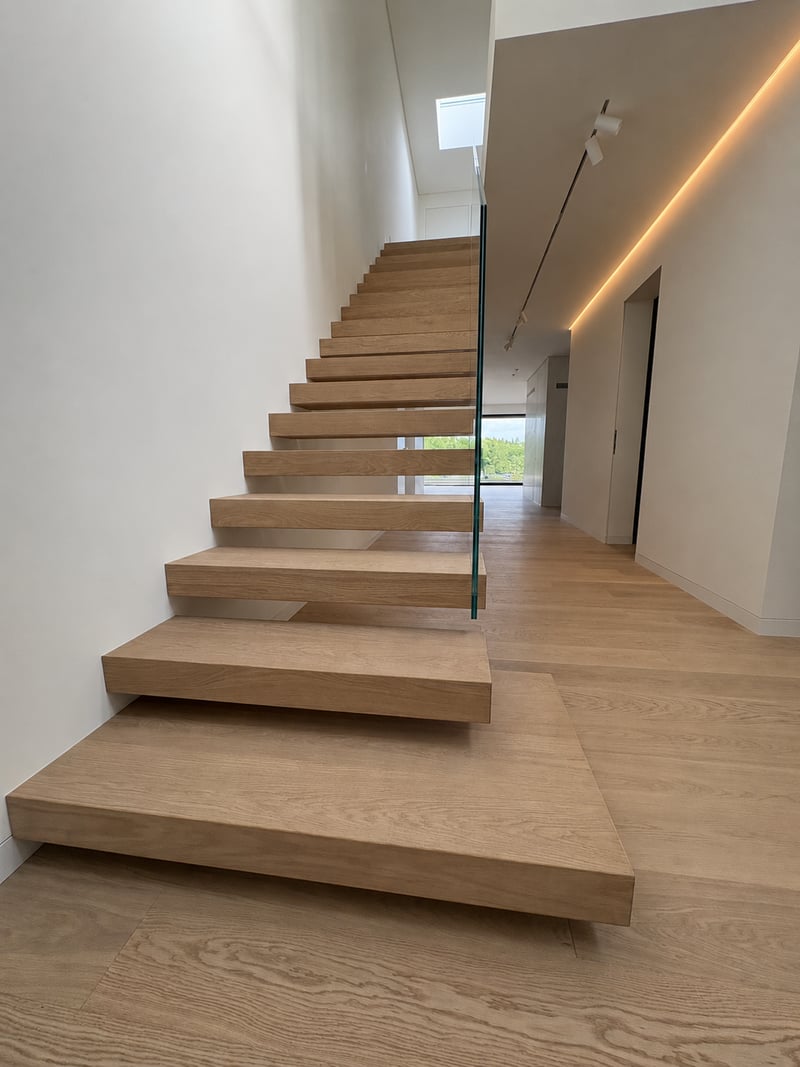 Kragarmtreppe mit Eichenstufen und rahmenlosem Glasgeländer in Frankfurt am Main